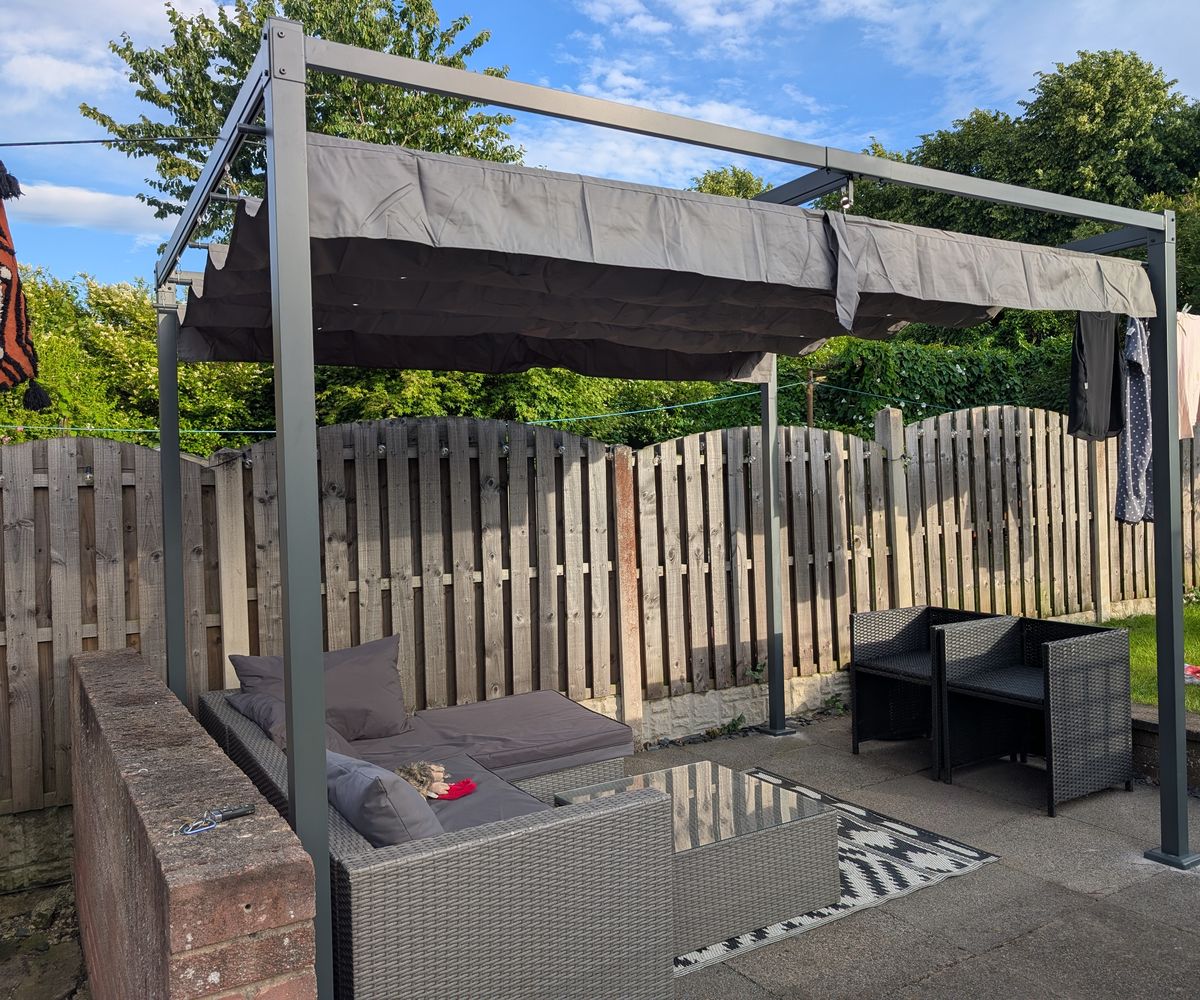 Metal pergola with a retractable canopy installed over a patio seating area