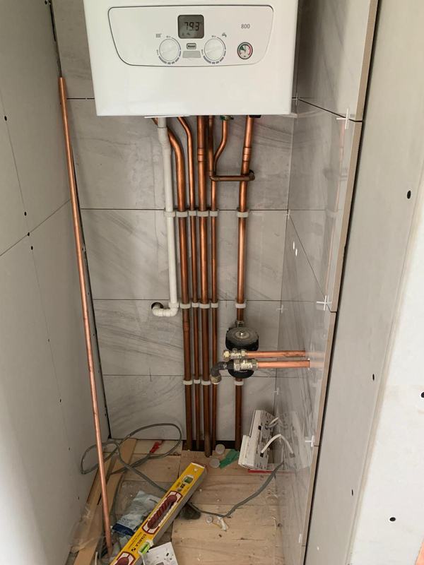 Wall-mounted combi boiler with neatly clipped copper pipework beneath it