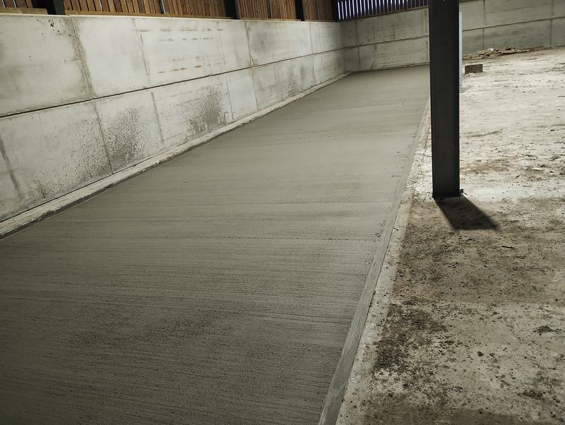 Freshly laid concrete floor beside concrete panel walls in a farm building