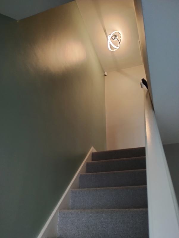 Illuminated ring-style ceiling light above a carpeted staircase