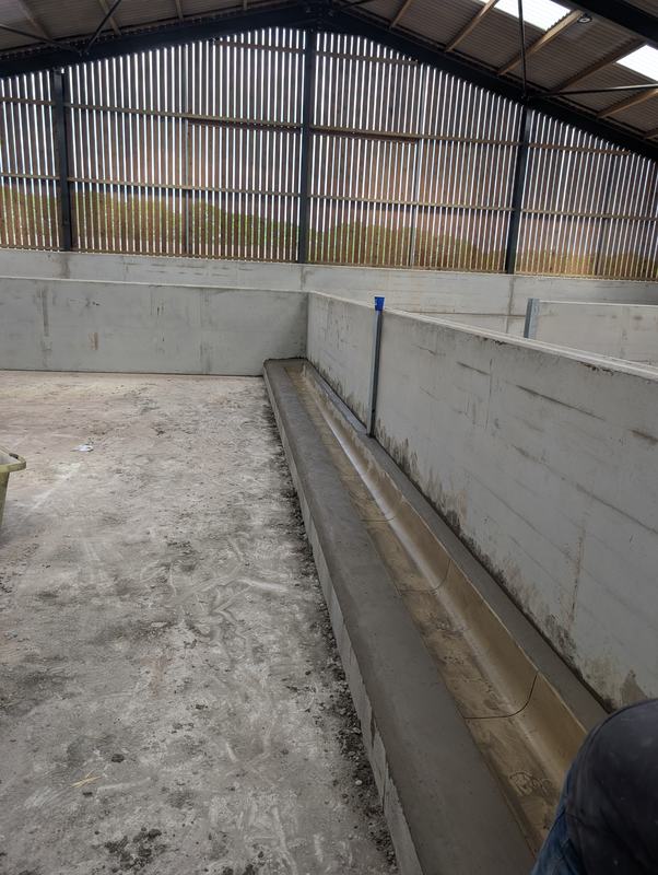 Concrete trough running along a wall inside a farm building