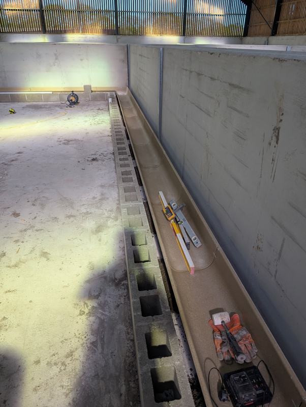 Trough being levelled alongside a blockwork edge inside a farm building