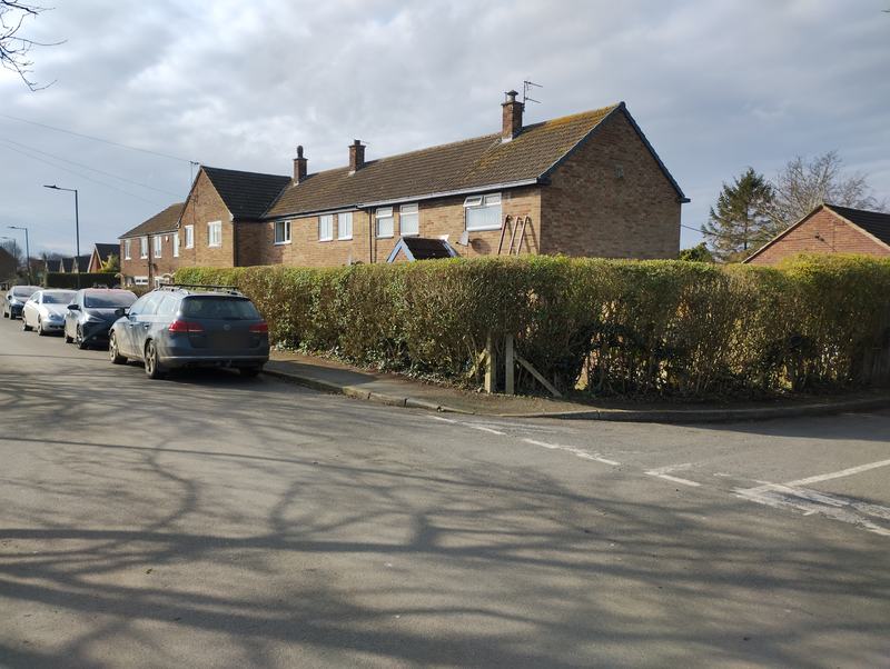 Boundary hedge cut back to a neat flat top at a street corner