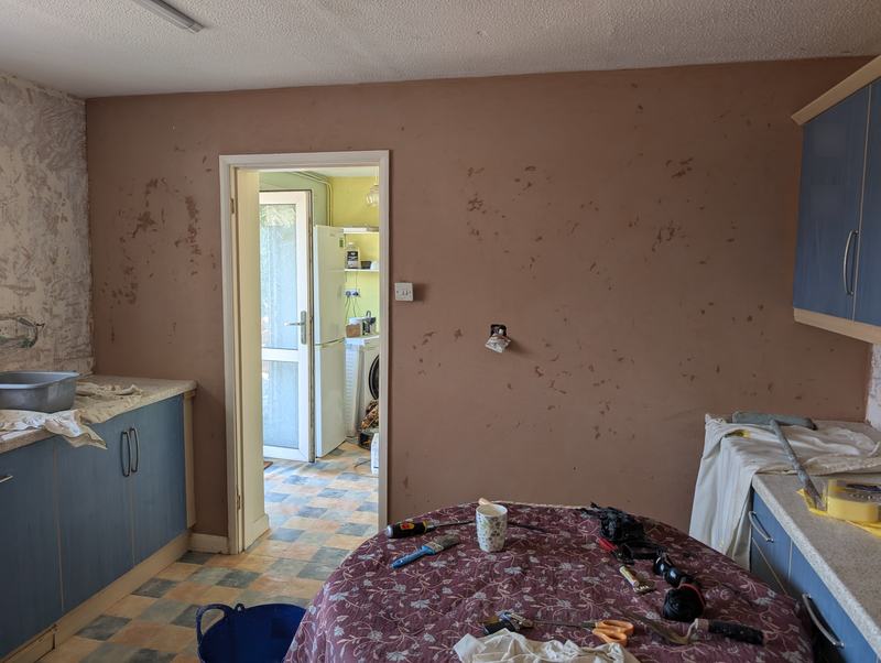 Kitchen with newly plastered walls and a doorway through to a utility room