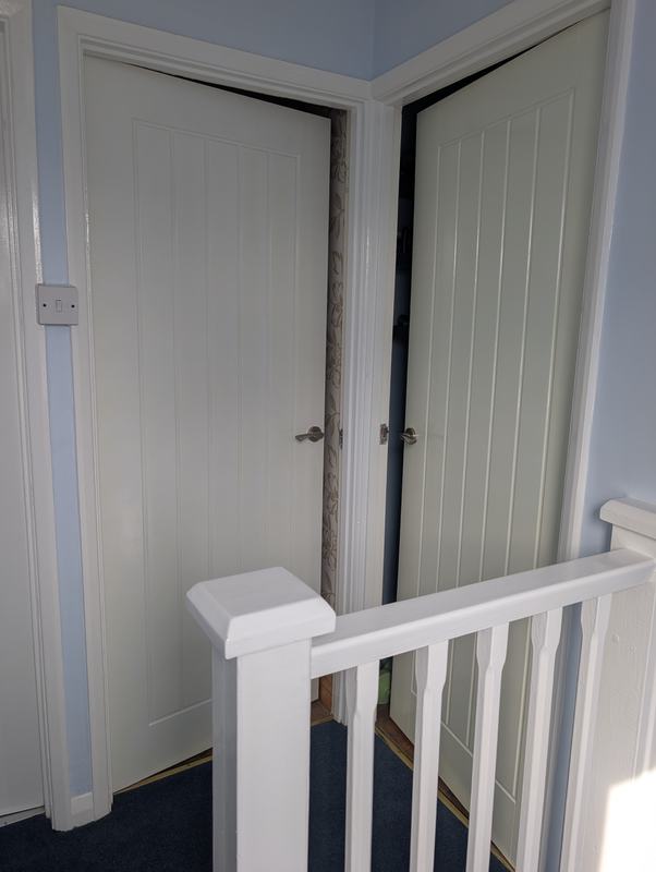 Landing with two painted doors, a white banister and pale blue walls