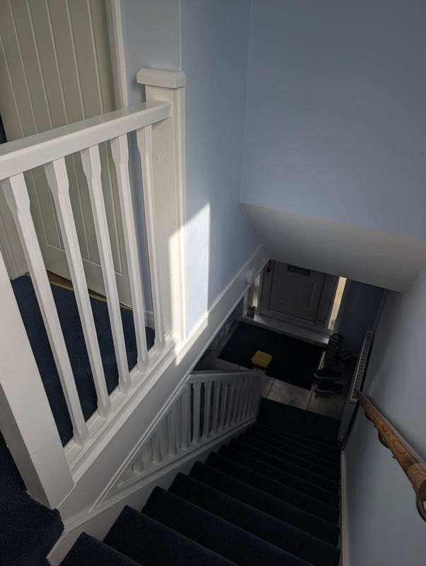 White painted banister and spindles above a carpeted staircase with pale blue walls