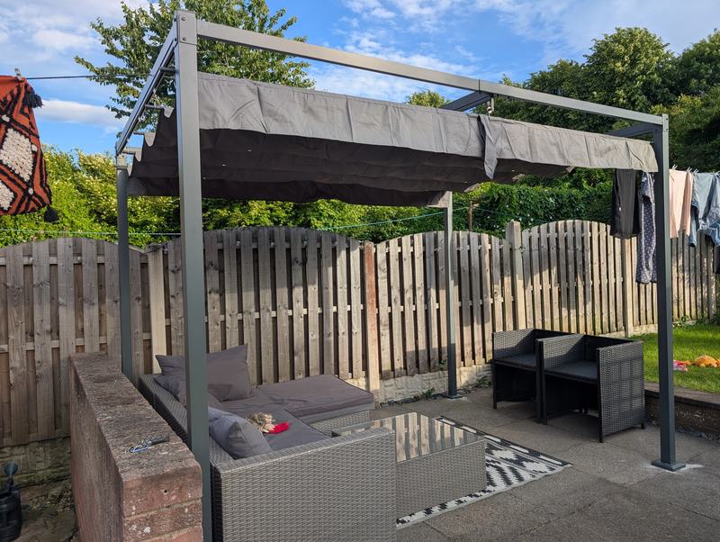 Metal pergola with a retractable canopy over a patio seating area