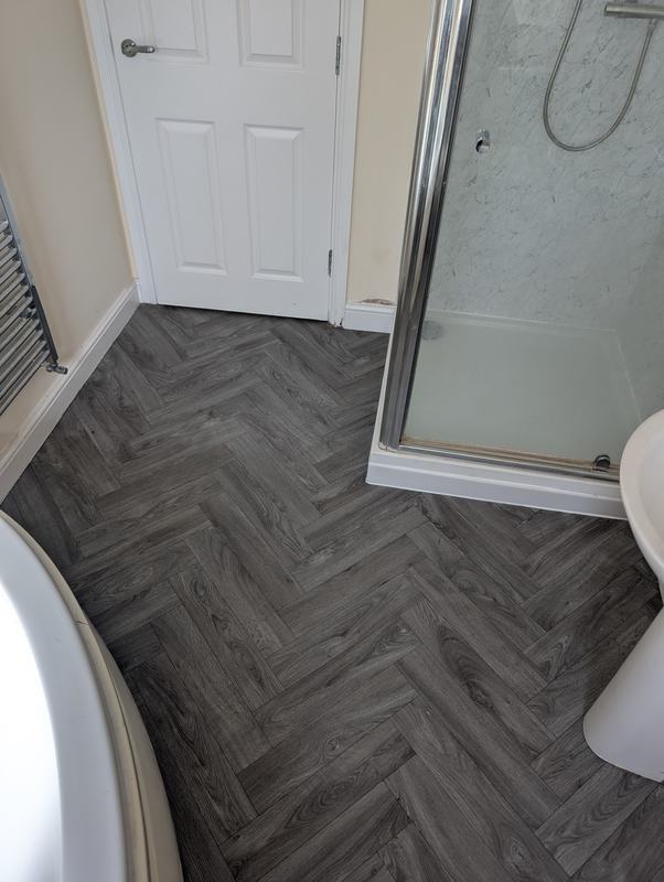 Finished bathroom with a herringbone-pattern floor and a new shower tray and enclosure