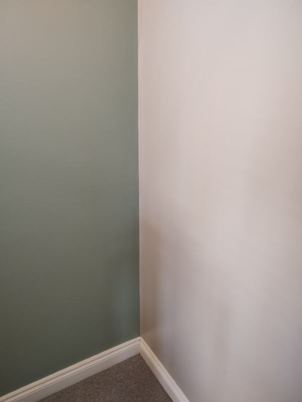 Sage green and cream walls meeting in a clean painted corner above white skirting