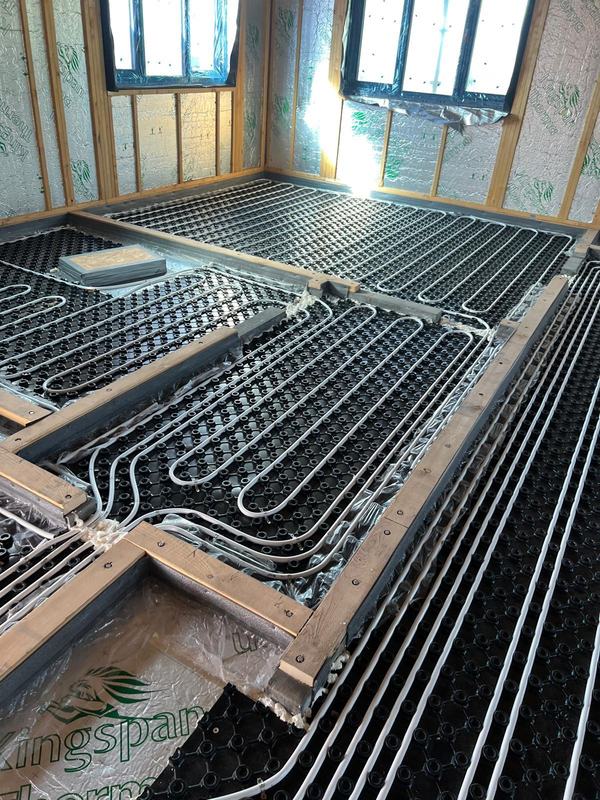 Underfloor heating pipe laid in loops on studded boards inside a timber frame