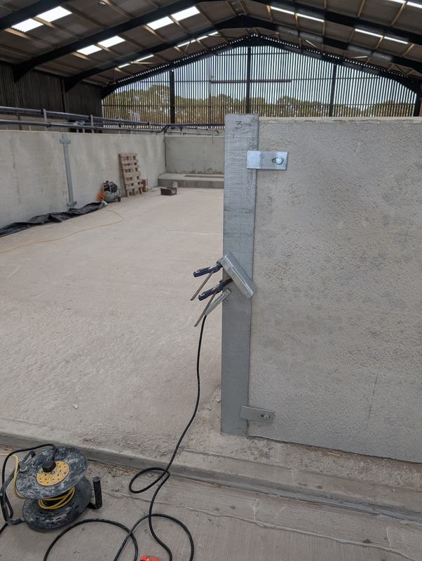 Galvanised steel post with brackets clamped ready for welding in a farm building